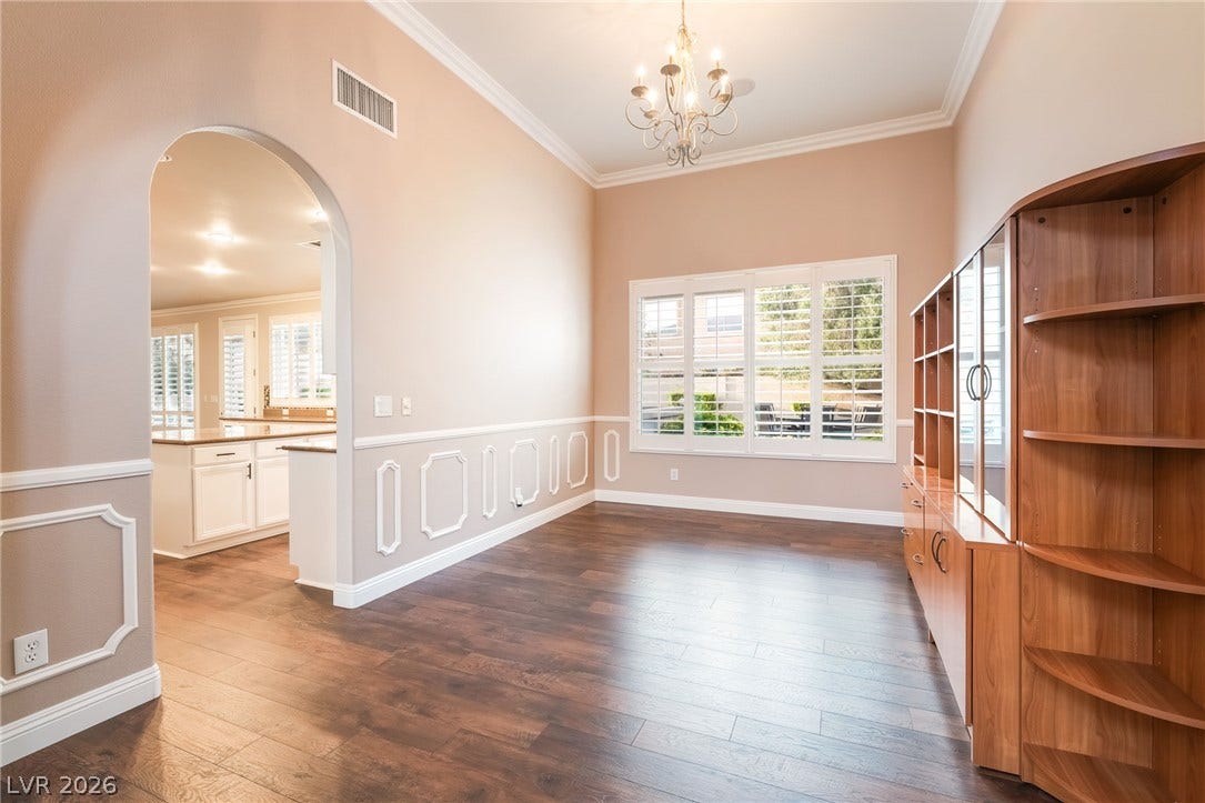 11416 Rancho Portena Avenue, Las Vegas, NV 89138 An arched doorway leads to the kitchen, highlighting detailed wainscoting and warm wood floors.