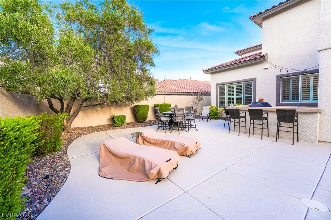 11416 Rancho Portena Avenue, Las Vegas, NV 89138 Concrete patio slabs stretch alongside an outdoor bar counter built against stucco walls.