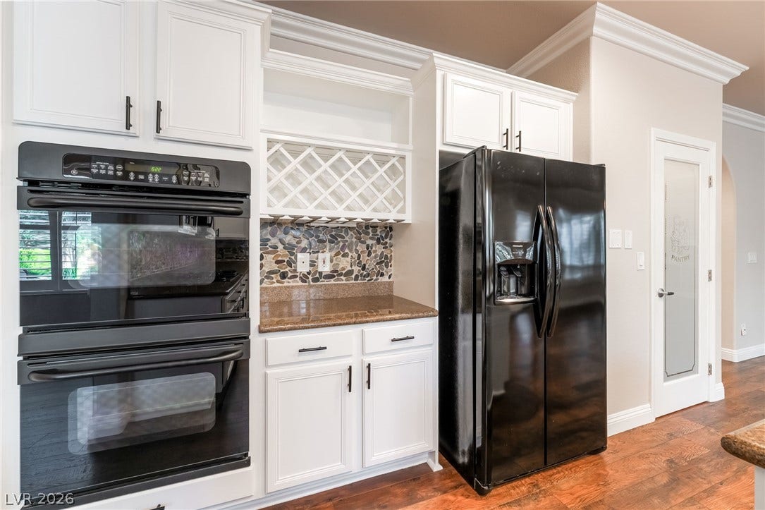 11416 Rancho Portena Avenue, Las Vegas, NV 89138 Rich hardwood flooring anchors custom cabinetry, a built-in wine rack, and professional crown molding details.