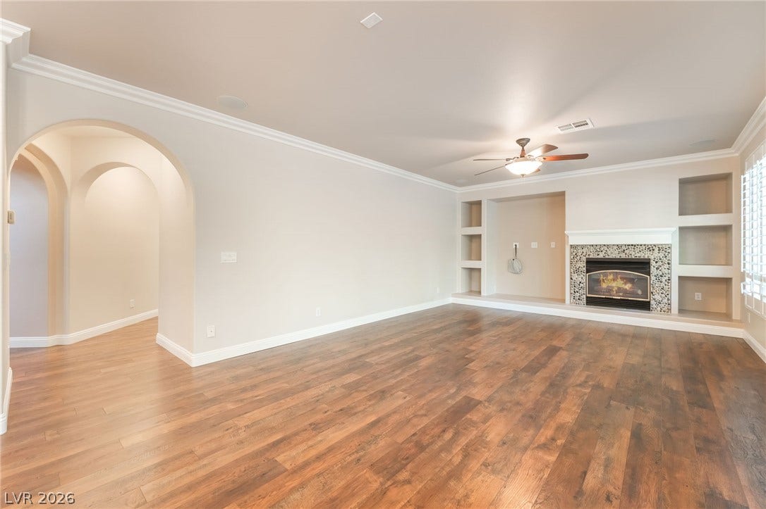 11416 Rancho Portena Avenue, Las Vegas, NV 89138 Rich hardwood flooring complements a fireplace with stone surround and elegant arched entryways.