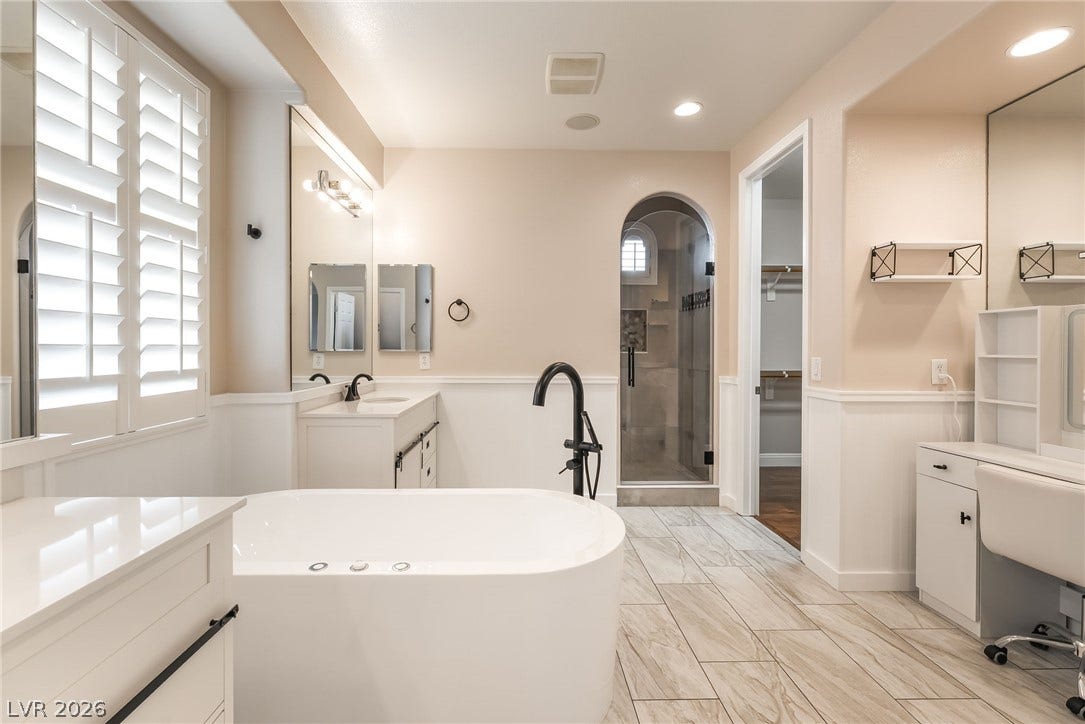 11416 Rancho Portena Avenue, Las Vegas, NV 89138 Polished tile flooring, a freestanding soaking tub, and an arched walk-in shower define this bath.