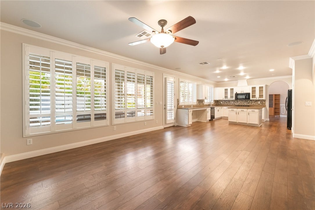 11416 Rancho Portena Avenue, Las Vegas, NV 89138 Rich wood flooring connects the spacious living area to a bright kitchen beyond.