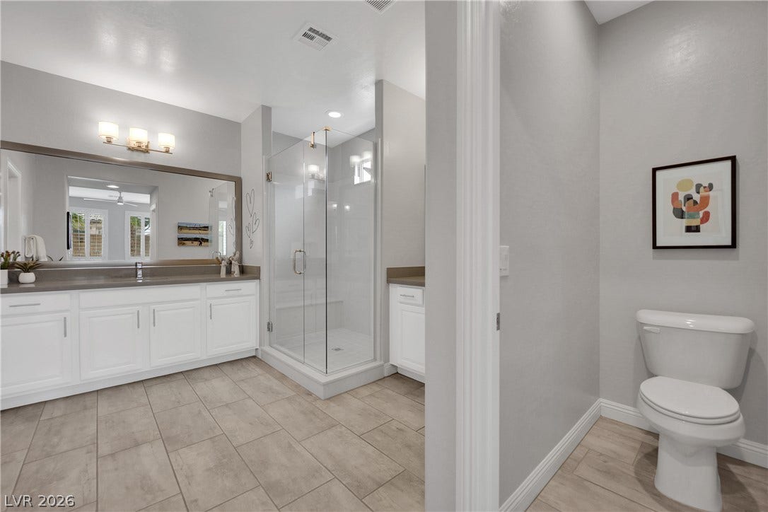 A well-lit bathroom showcases a spacious vanity, large mirror, and walk-in shower, offering comfort and style.