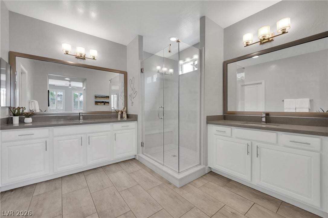 Dual vanities with stone counters and a spacious glass-enclosed shower create a tranquil retreat.