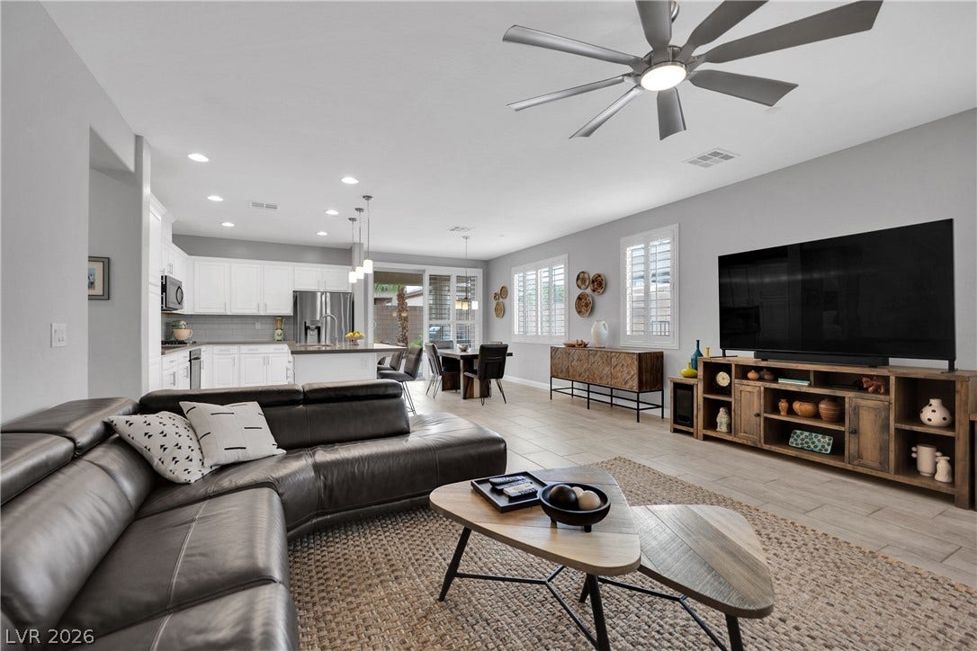 An open-concept living area seamlessly connects the kitchen and dining spaces, illuminated by recessed lighting and a striking ceiling fan.