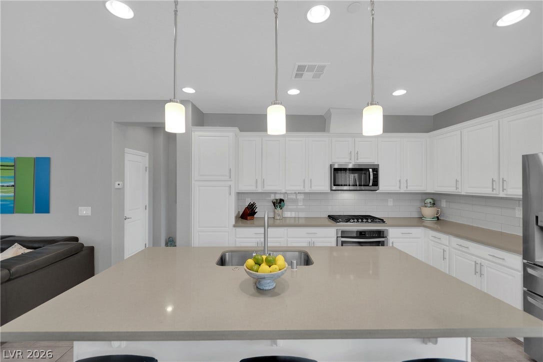 Modern kitchen features a spacious island with sink and sleek stainless steel appliances, ideal for culinary creations.