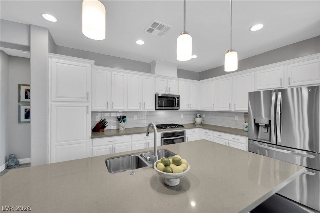 Culinary delights await in this bright, well-appointed kitchen featuring a substantial island with sink and stainless steel appliances.