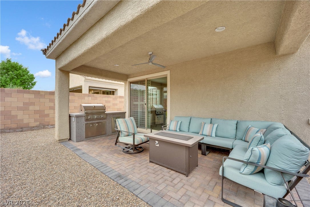 An inviting outdoor living area features a built-in barbecue and comfortable seating beneath a covered patio.