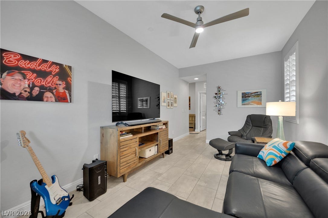 Modern living space with a ceiling fan, window shutters, and sleek tile flooring for comfort.