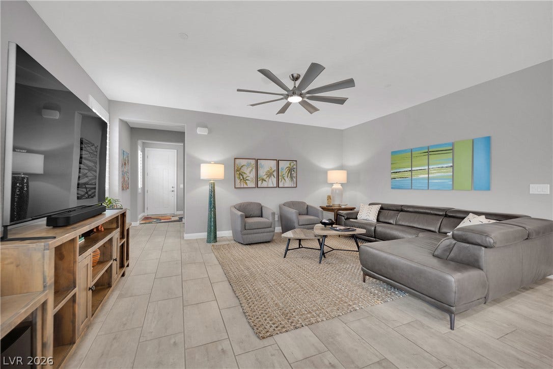 An inviting living area features neutral tones and light wood-look tile flooring.