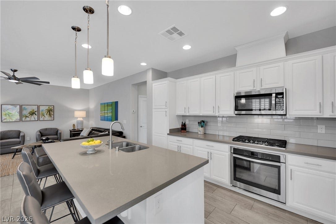 A contemporary kitchen and living area blend seamlessly with sleek cabinetry and warm lighting.