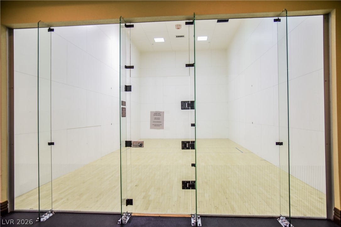 Smooth wood flooring and tall glass walls define this private indoor court.