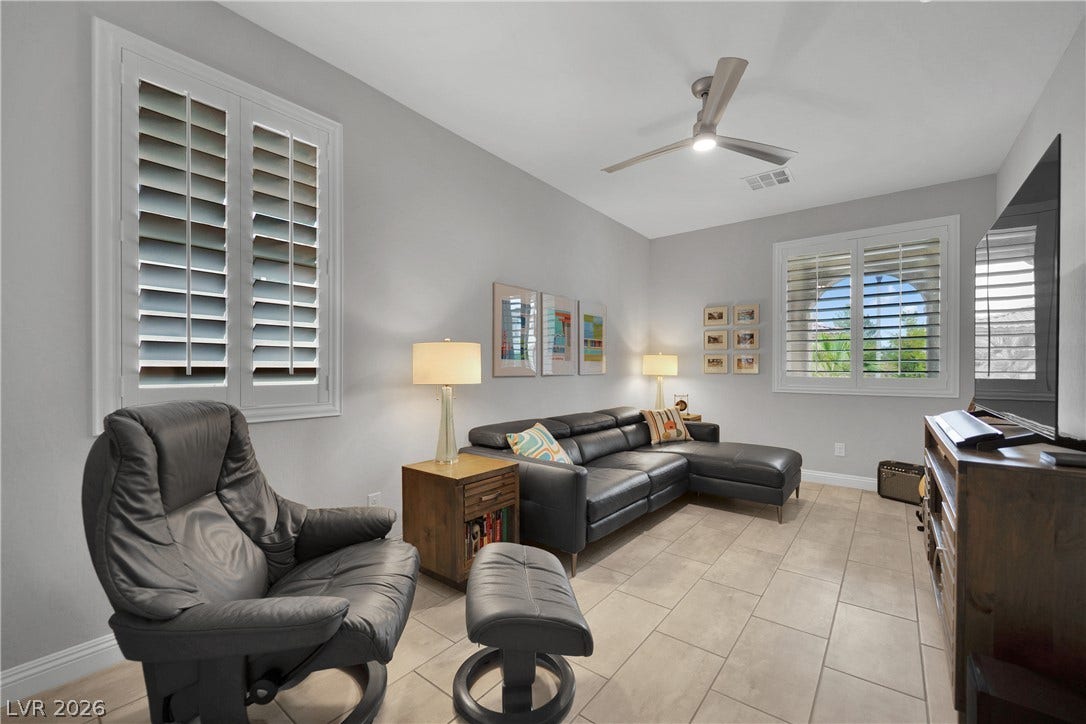 Relax in this comfortable living room featuring elegant window shutters and modern tiled flooring.