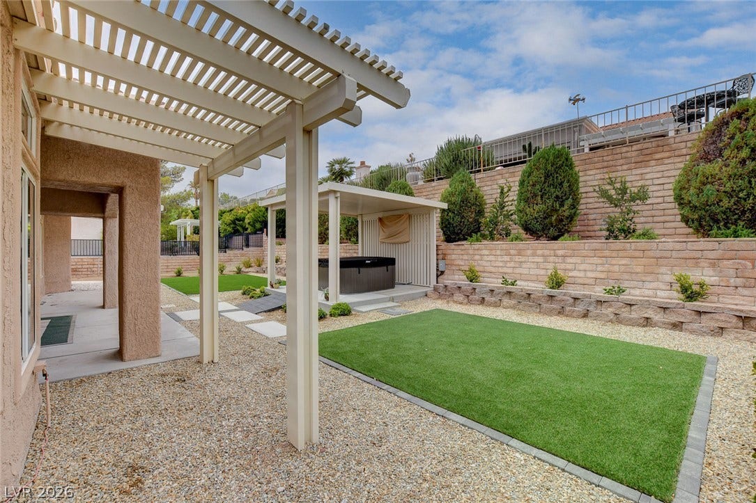 2621 Hanging Rock Drive, Las Vegas, NV 89134 An inviting backyard features a shaded patio, gravel paths, and a terraced retaining wall.