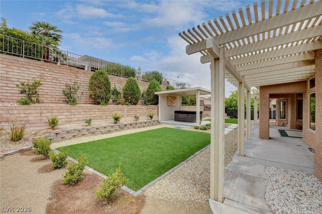 2621 Hanging Rock Drive, Las Vegas, NV 89134 An inviting backyard features a structured pergola, tidy artificial turf, and a covered spa area.