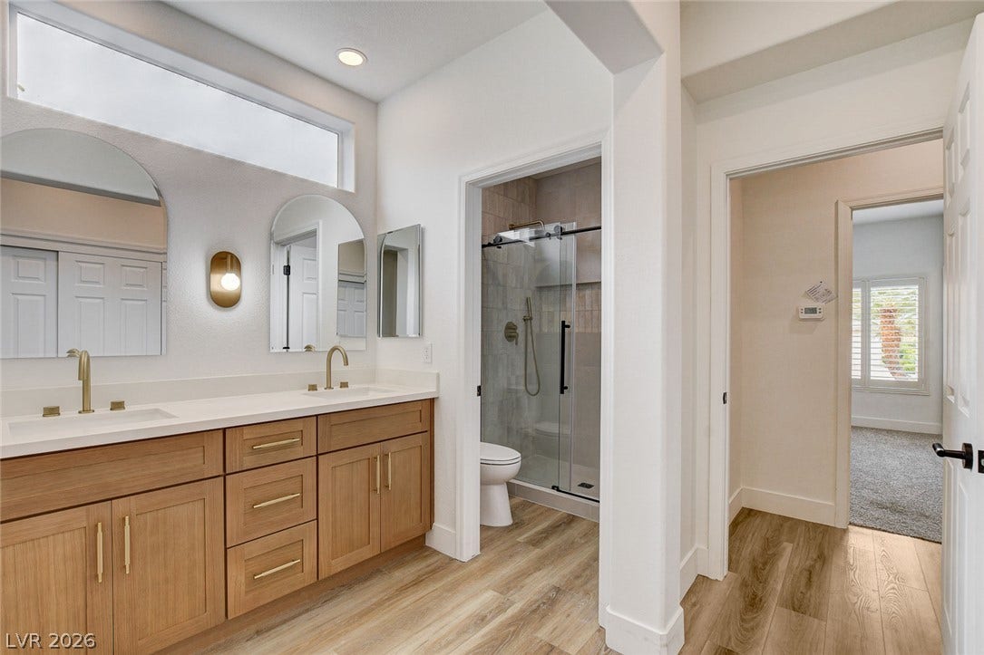 2621 Hanging Rock Drive, Las Vegas, NV 89134 A double vanity with light wood cabinetry and high ceilings elevates this refined bathroom space.