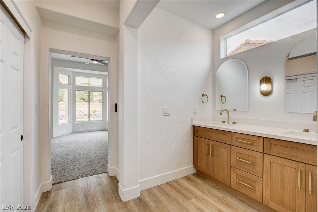 2621 Hanging Rock Drive, Las Vegas, NV 89134 Smooth wood-look flooring and a dual vanity with stone counters define this modern washroom.