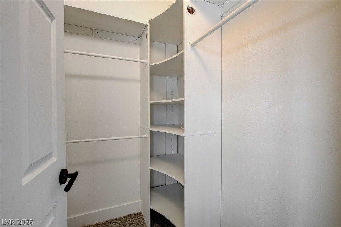 2621 Hanging Rock Drive, Las Vegas, NV 89134 Custom built-in shelving and dual hanging rods maximize storage in this carpeted walk-in closet.