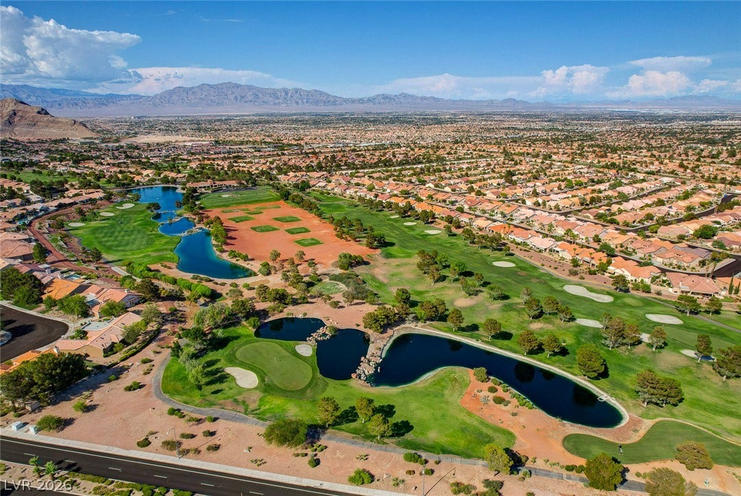 2621 Hanging Rock Drive, Las Vegas, NV 89134 An expansive valley community surrounds a lush green golf course featuring shimmering blue water hazards.