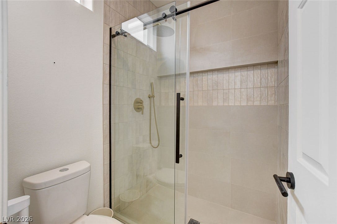 2621 Hanging Rock Drive, Las Vegas, NV 89134 A modern walk-in shower features glass doors and stylish textured wall tiles.