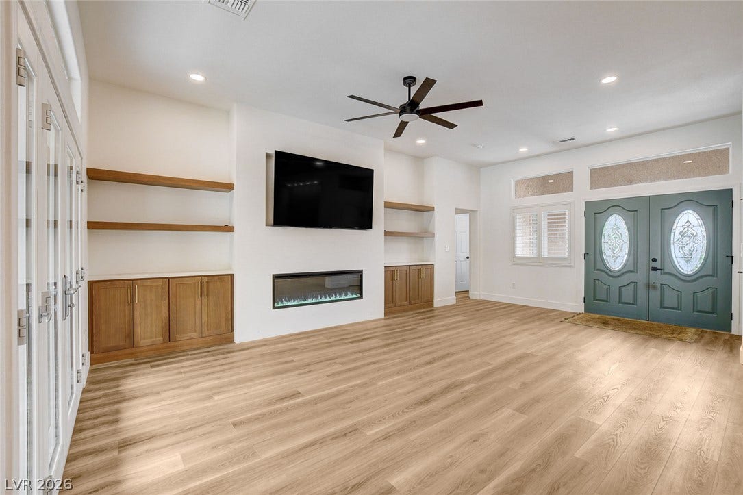 2621 Hanging Rock Drive, Las Vegas, NV 89134 An open living space highlights a linear fireplace alongside custom built-in shelving and hardwood flooring.