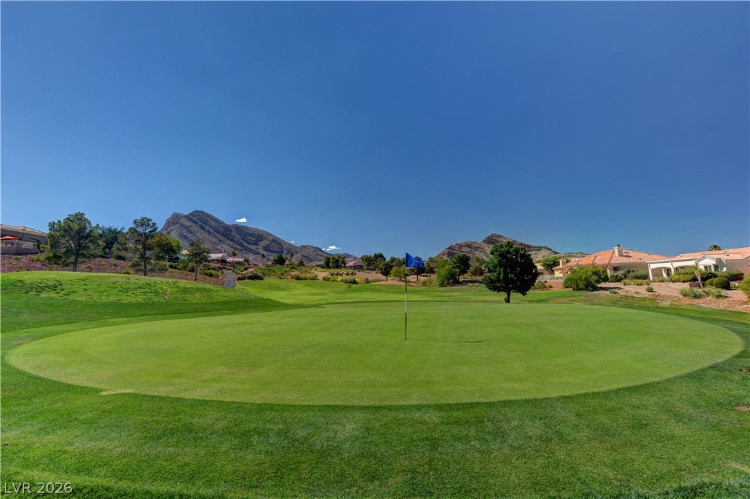 2621 Hanging Rock Drive, Las Vegas, NV 89134 Lush fairways stretch toward rolling hills and majestic mountain peaks under clear blue skies.
