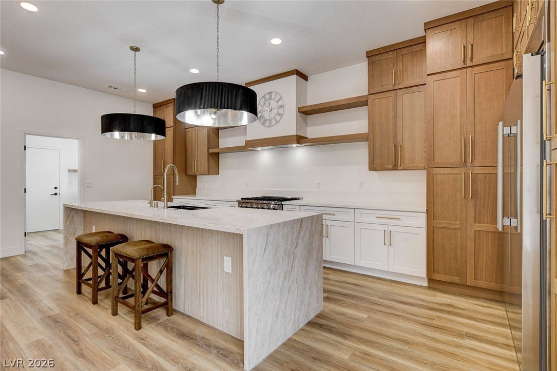 2621 Hanging Rock Drive, Las Vegas, NV 89134 Warm wood cabinetry and a marble waterfall island define this modern culinary space.