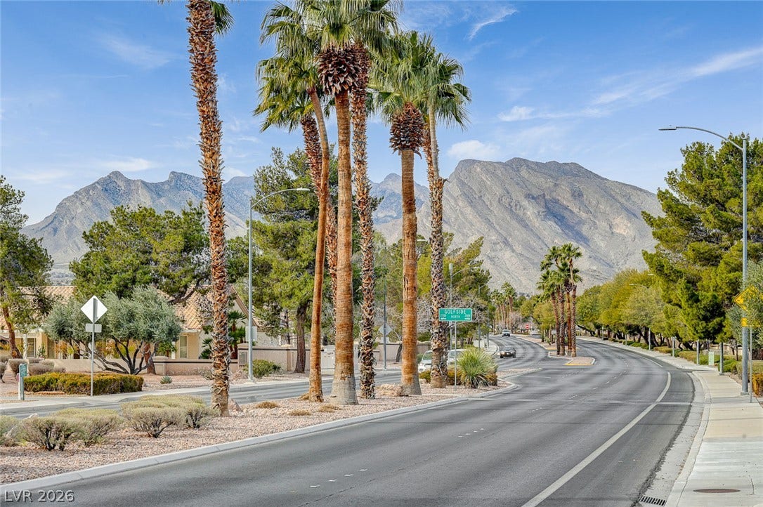2621 Hanging Rock Drive, Las Vegas, NV 89134 Towering palm trees and a paved roadway frame breathtaking mountain views under blue skies.