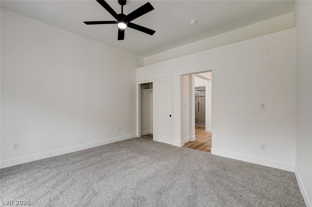 2621 Hanging Rock Drive, Las Vegas, NV 89134 Plush carpeting anchors this spacious bedroom featuring high ceilings and a walk-in closet entryway.