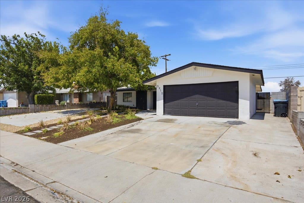 3912 Casa Grande Avenue, Las Vegas, NV 89102 An expansive concrete driveway leads to a two-car garage on a clear, sunny day.