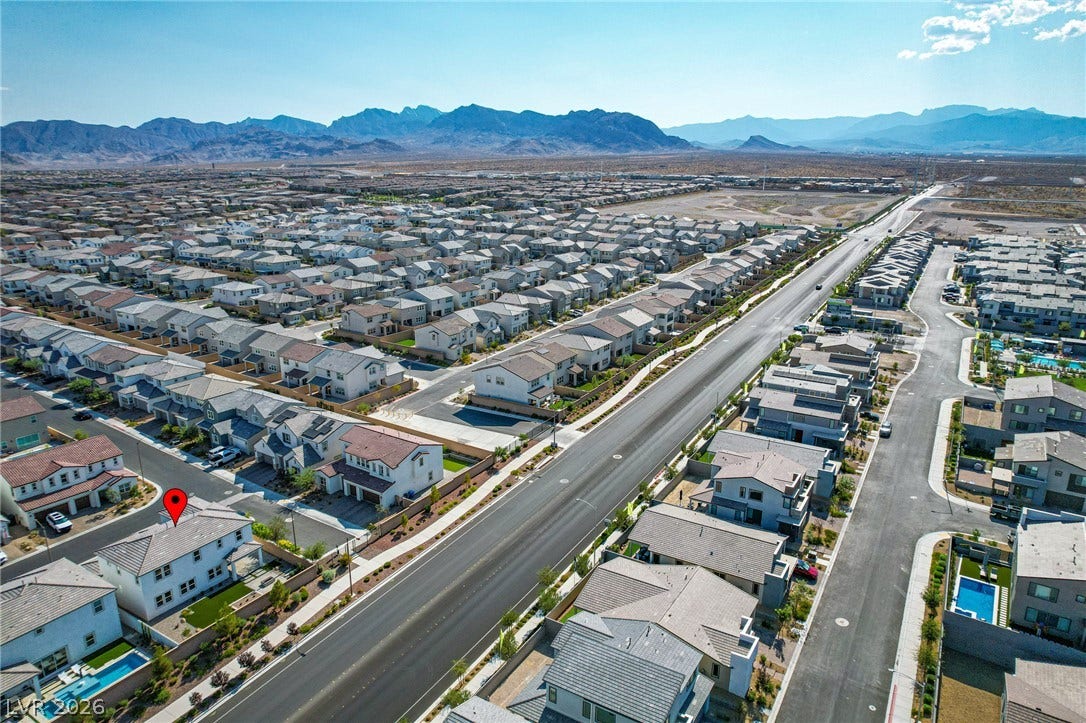 10226 Pleasant Knoll Avenue, Las Vegas, NV 89166 A sweeping aerial view showcases the neighborhood layout with majestic mountains on the horizon.