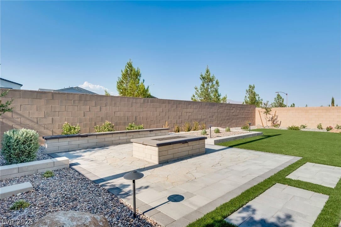 10226 Pleasant Knoll Avenue, Las Vegas, NV 89166 A spacious backyard features a paved patio, built-in stone fire pit, and low-maintenance landscaping.