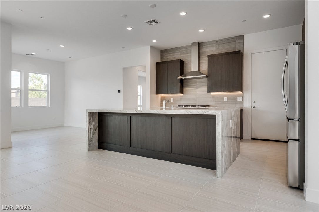 10226 Pleasant Knoll Avenue, Las Vegas, NV 89166 Streamlined kitchen design centers on a waterfall island under recessed lighting.