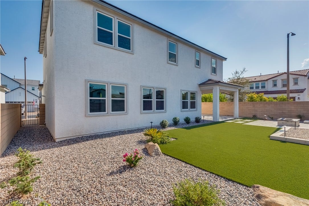 10226 Pleasant Knoll Avenue, Las Vegas, NV 89166 A manicured backyard features synthetic turf, gravel landscaping, and a covered patio area.