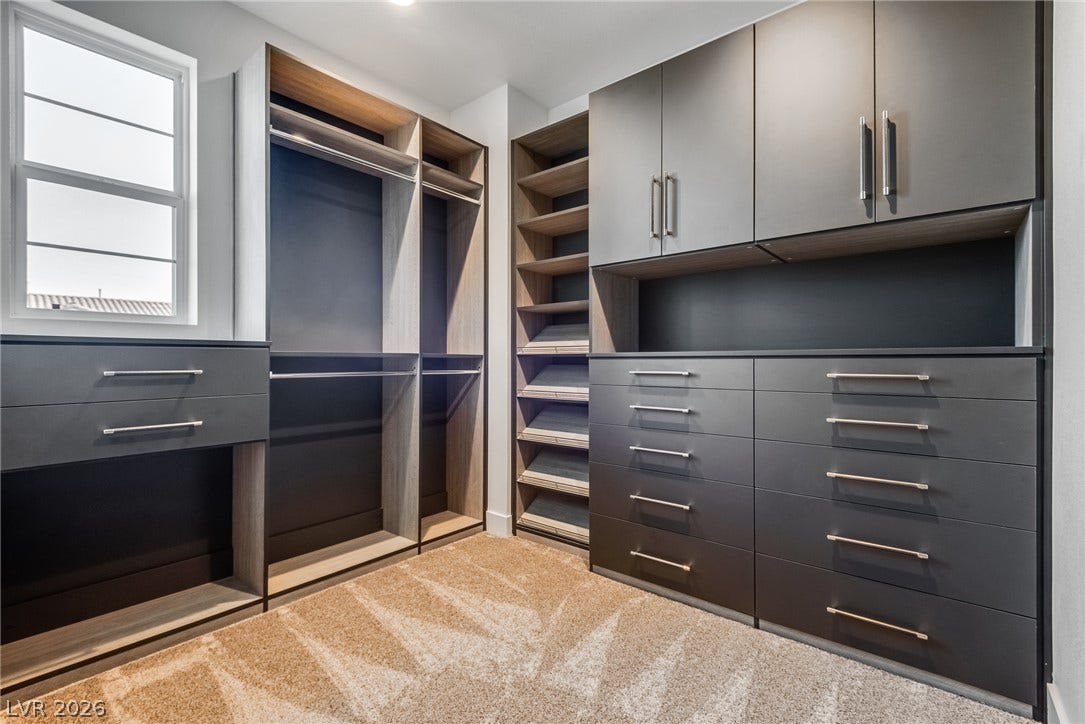 10226 Pleasant Knoll Avenue, Las Vegas, NV 89166 Sleek custom cabinetry and plush carpeting define this organized walk-in closet space.