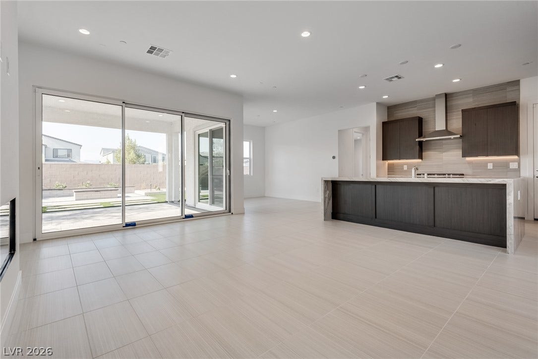 10226 Pleasant Knoll Avenue, Las Vegas, NV 89166 A spacious open layout connects the living area to a modern kitchen with sliding glass doors.