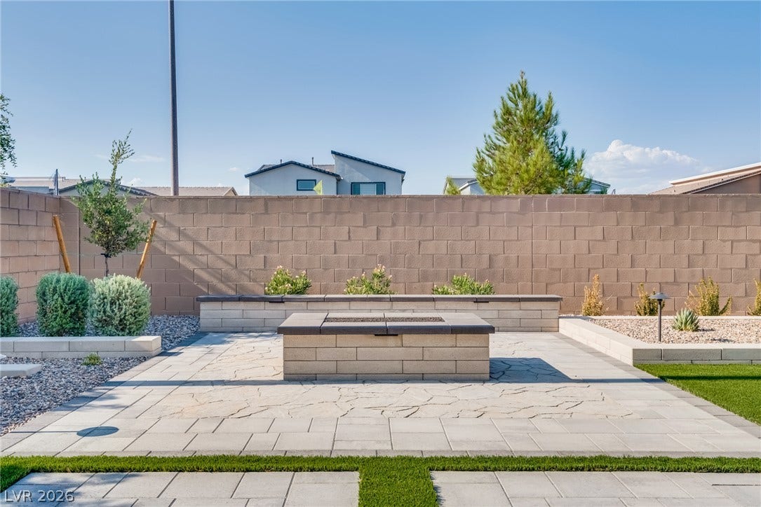 10226 Pleasant Knoll Avenue, Las Vegas, NV 89166 An inviting stone fire pit area sits on paved stone inside a fenced backyard.