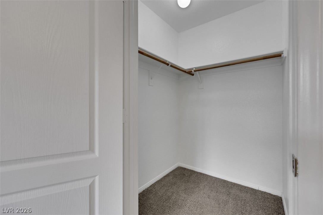 657 Anne Lane, #657, Henderson, NV 89015 A spacious walk-in closet includes carpet flooring and functional hanging rods.