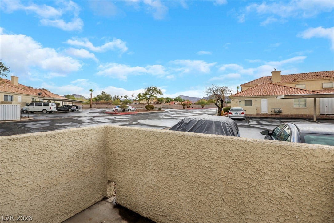 657 Anne Lane, #657, Henderson, NV 89015 A private outdoor patio overlooks the neighborhood parking lot and stucco residential structures under blue skies.