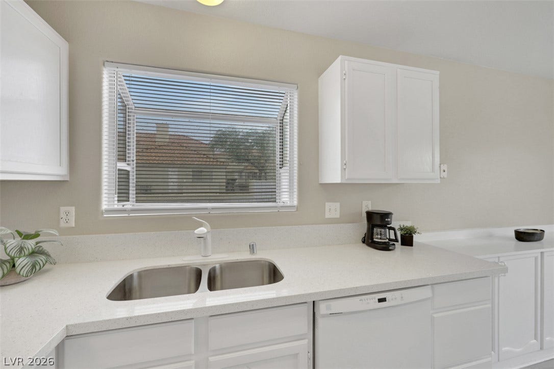 657 Anne Lane, #657, Henderson, NV 89015 Solid stone countertops and white cabinetry frame a classic double basin sink under natural light.