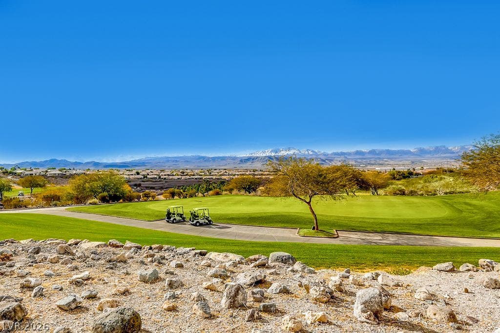 2284 Savannah River Street, Henderson, NV 89044 Sweeping views of a manicured green fairway unfold against a majestic mountain backdrop.