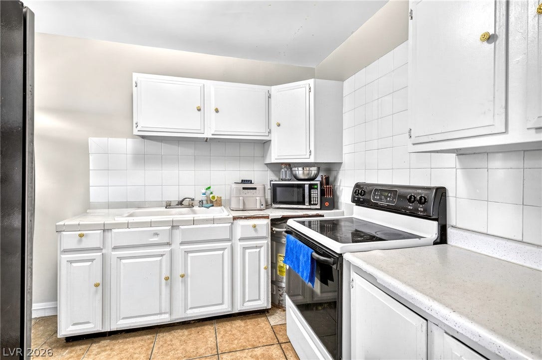 Crisp tiled surfaces and classic cabinetry define this functional cooking space.