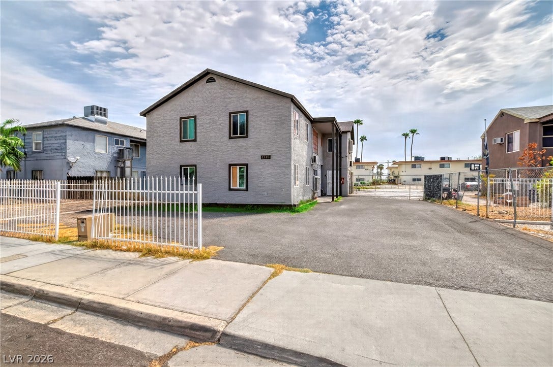 A stucco exterior defines this multi-family residential structure lined with protective fencing.