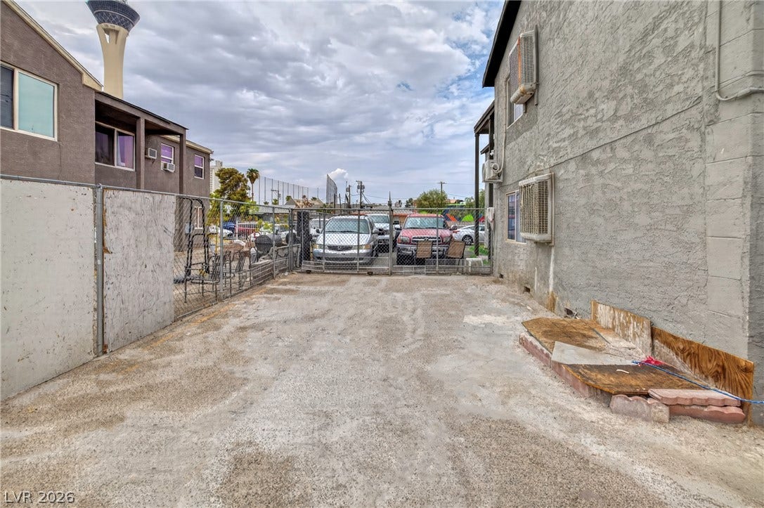 Fenced concrete driveway area connects the buildings under an open sky.
