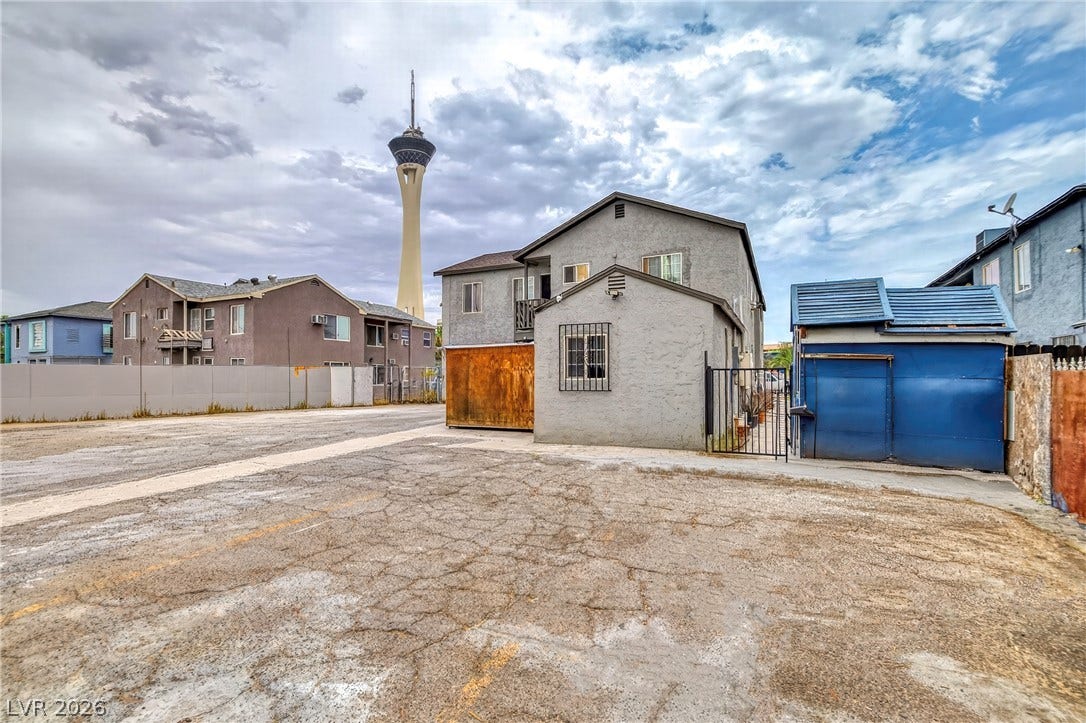 Multi-level residential structures surround a paved parking area set against a dramatic sky.