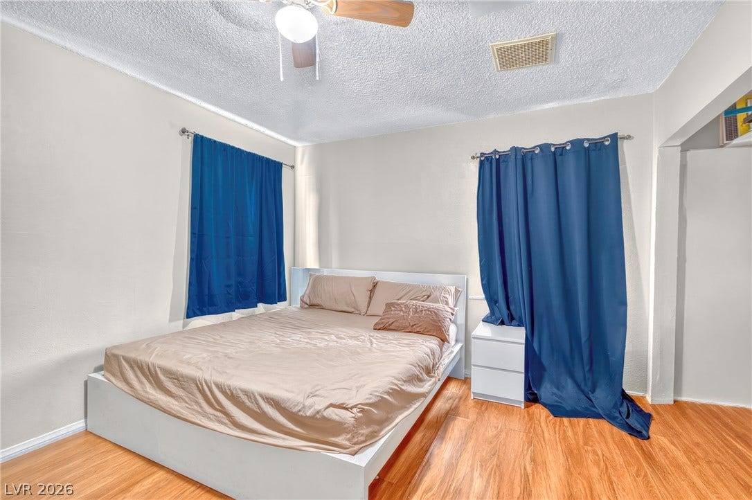 Warm wood flooring grounds this cozy bedroom layout.