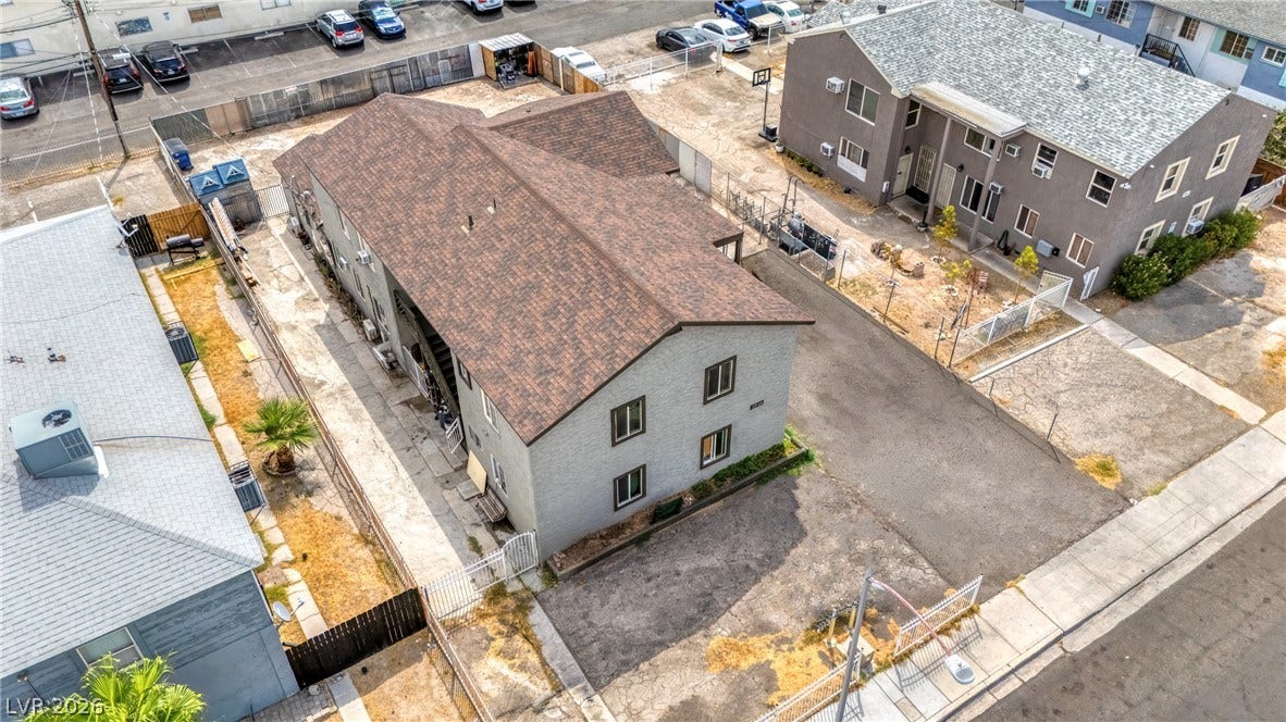 An aerial view showcases the multi-family structure with architectural composition and surrounding neighborhood layout.