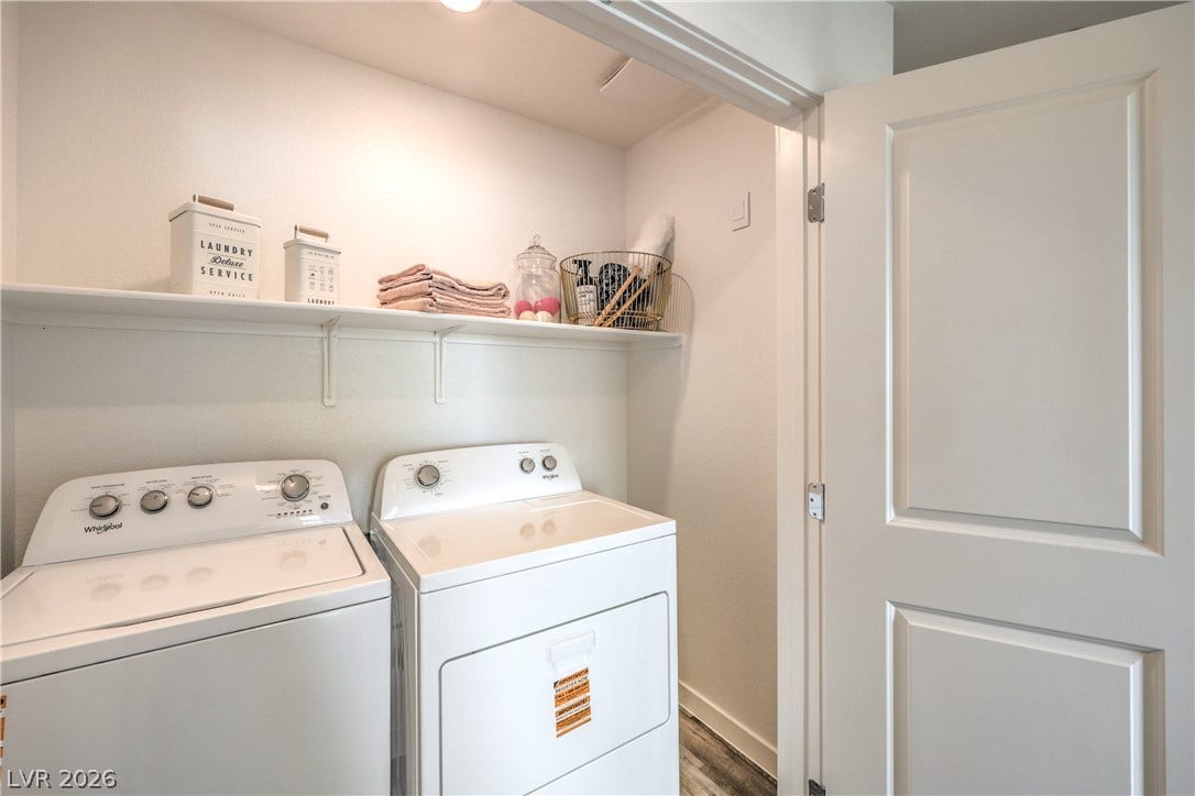906 Pink Sugarbird Street, Henderson, NV 89011 An organized laundry space features built-in shelving above coordinating appliances and durable plank flooring.