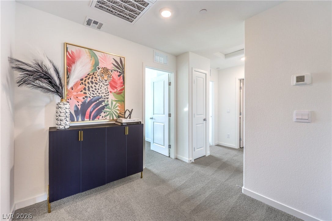 906 Pink Sugarbird Street, Henderson, NV 89011 Smooth plaster walls and soft carpeting define this welcoming transition hallway.