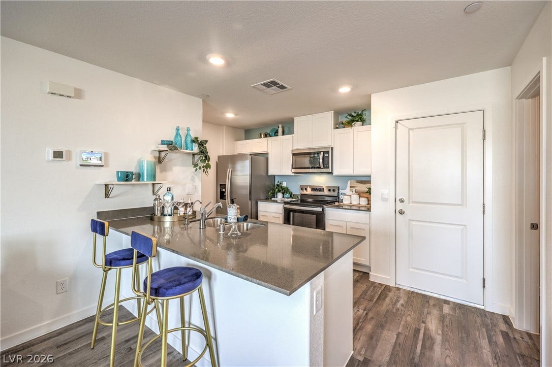 906 Pink Sugarbird Street, Henderson, NV 89011 Polished stone countertops complement clean cabinetry and durable wood-look flooring in this modern kitchen layout.